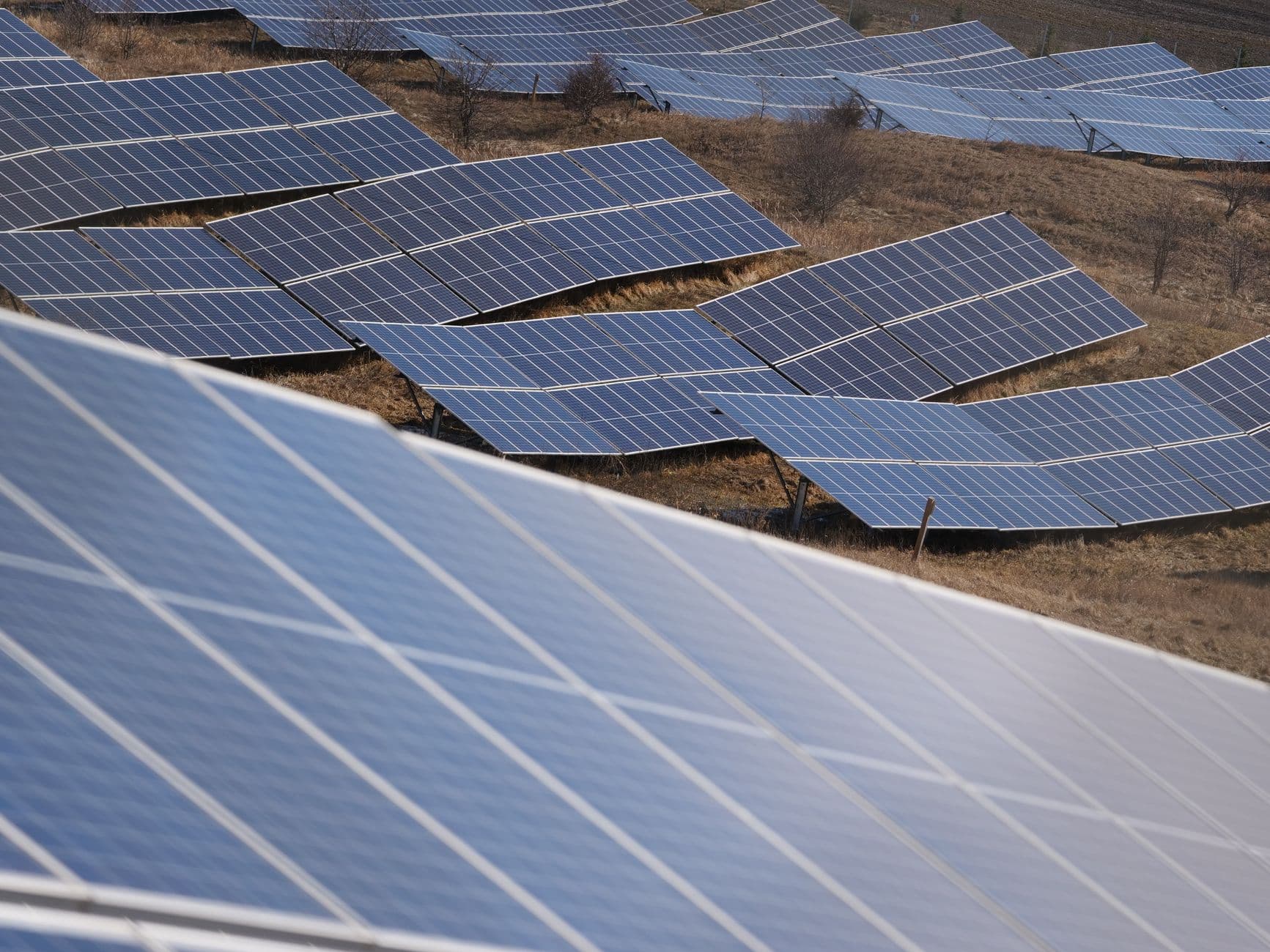 Aerial view of a large solar panel farm in an open field