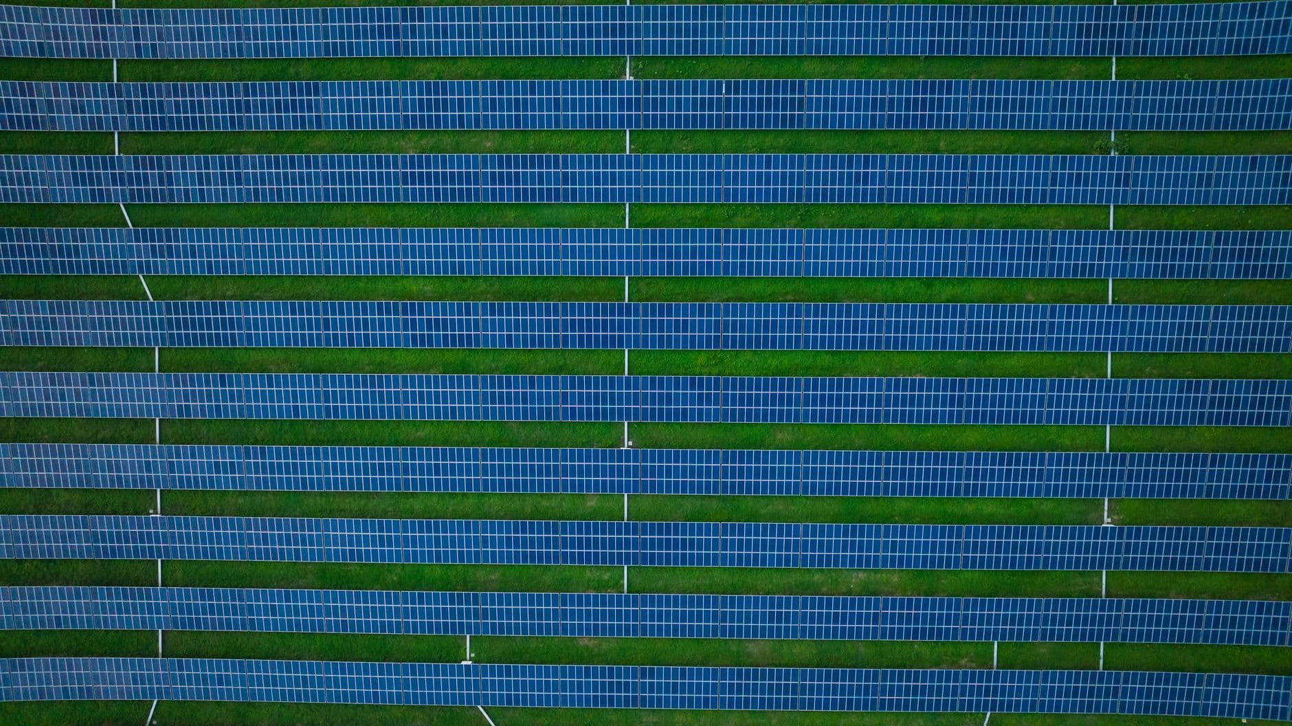 Aerial photograph of a solar farm with rows of panels and green spaces