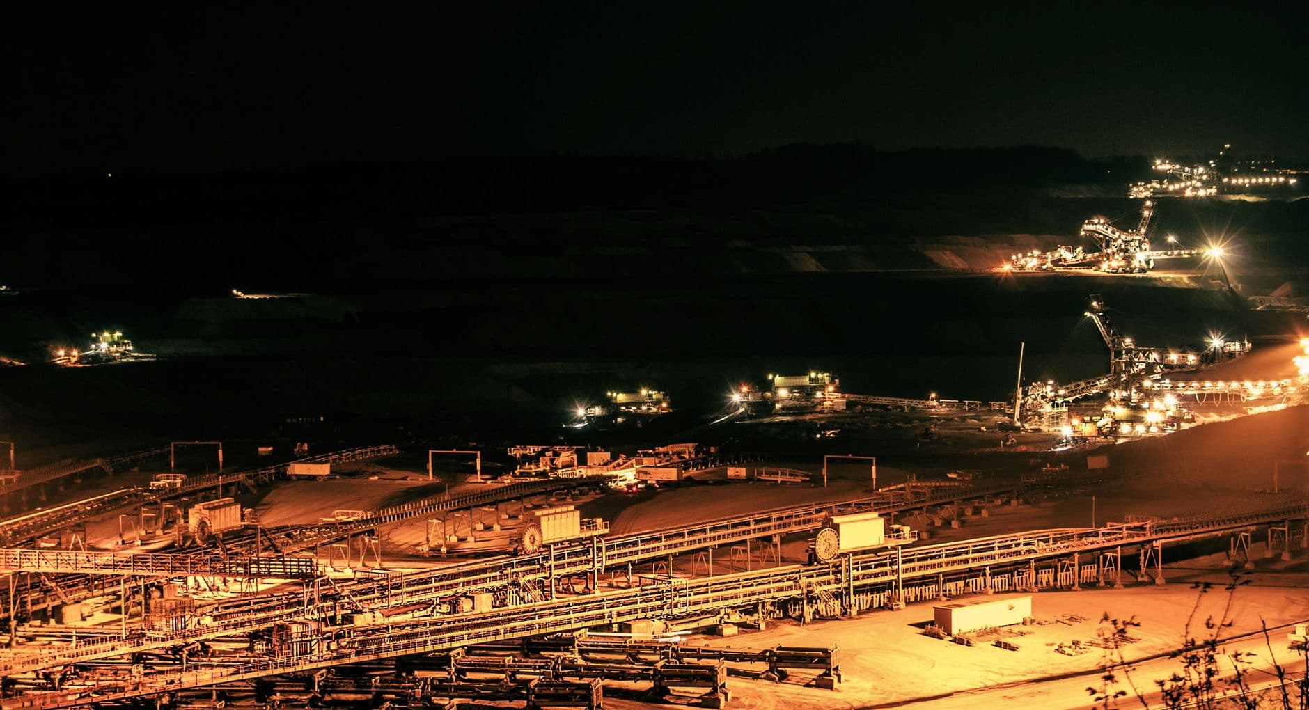 Aerial view of illuminated mining operations at night showing a large open-pit mine without visible diesel equipment