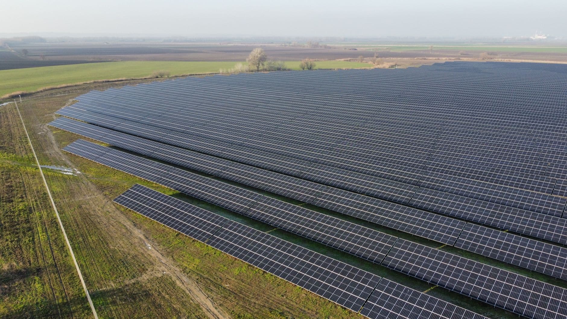 Aerial view of a large solar panel farm in a rural landscape under clear skies