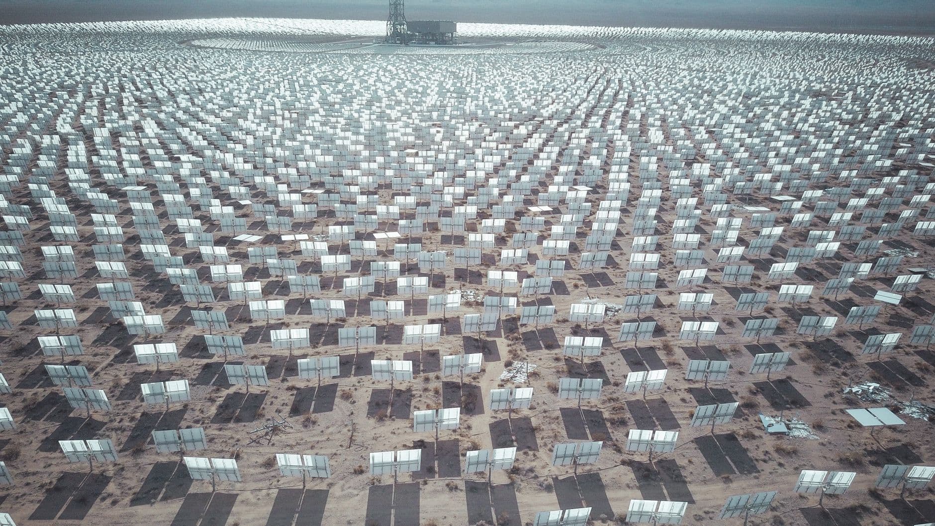 Aerial view of expansive solar panel array in a desert landscape generating renewable energy.